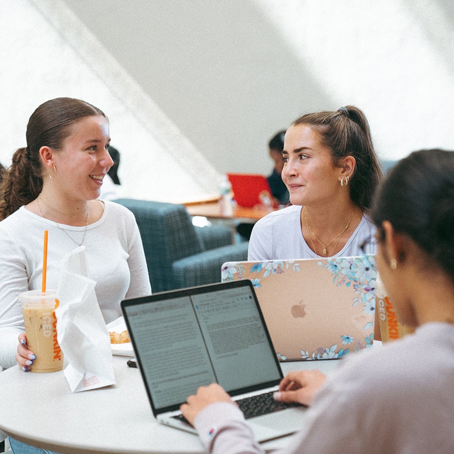 girls studying around table one looking at other who's holding coffee cup