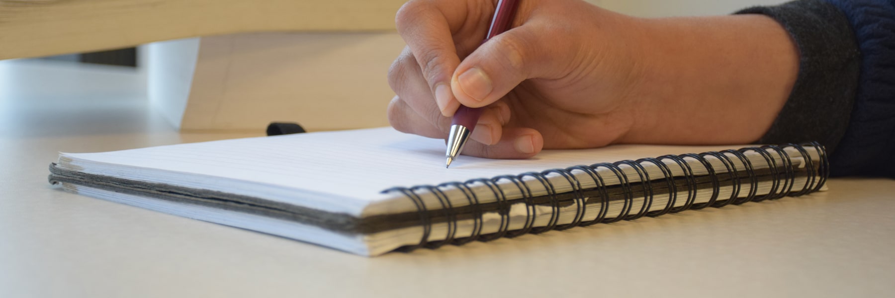 close up of person holding pen and writing on a notebook