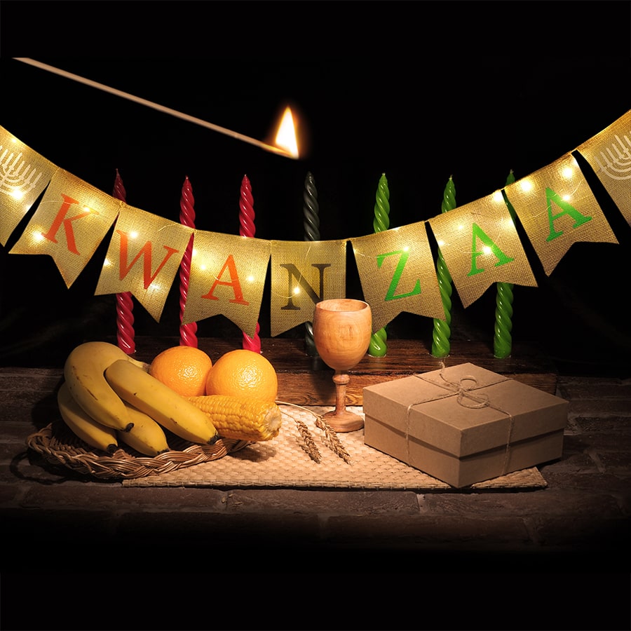 table of fruits, wine cup and candles with banner kwanzaa